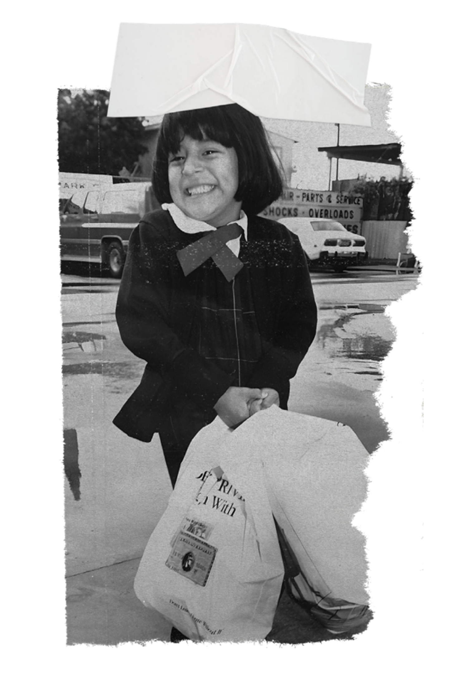 A young girl smiling broadly, holding two bags of groceries from the Los Angeles Regional Food Bank. She stands on a wet pavement, with an auto service shop in the background. The image has a torn and textured border, capturing a moment of community support and kindness.