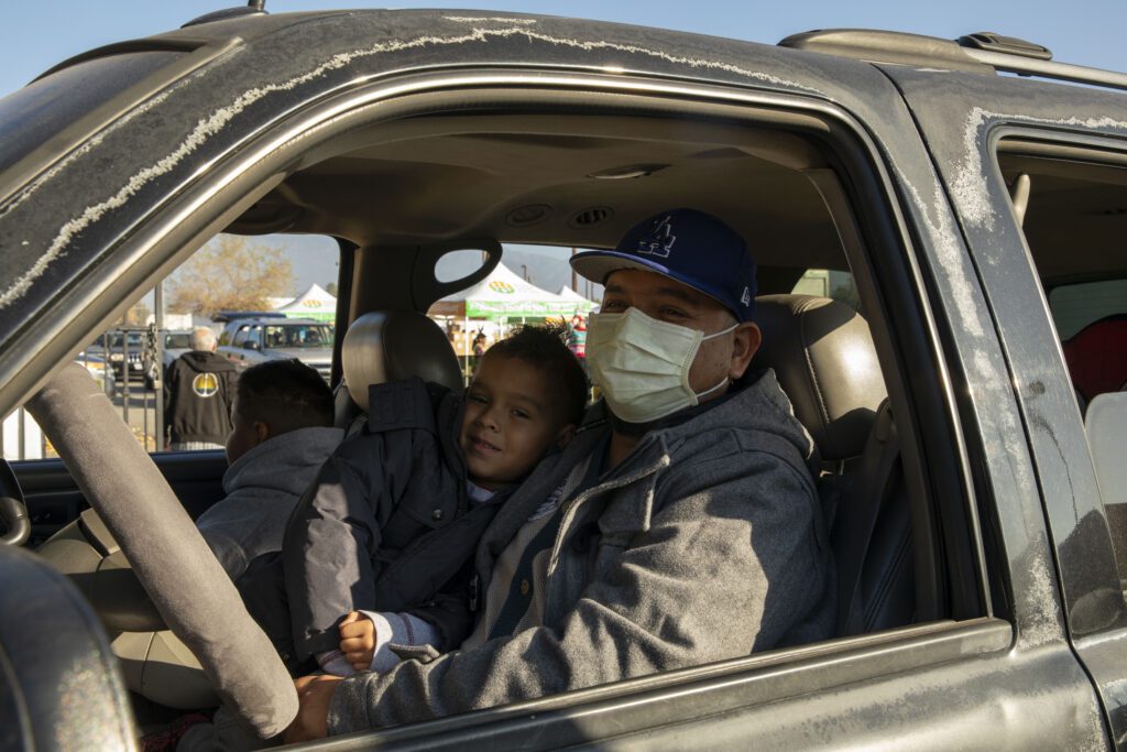 Julio with his young son at a food distribution at Sowing Seeds for Life in Pomona, California.