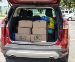 a food recipient in a red car has food boxes loaded onto trunk