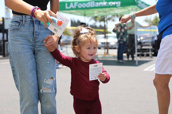A young girl is helping her parents make a donation during Feed SoCal.